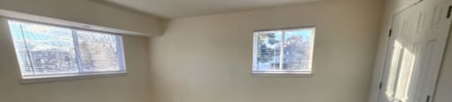 A room with carpeted floor and two windows.