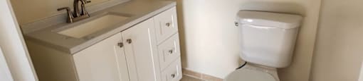 A white toilet sits in a bathroom next to a sink and a mirror.