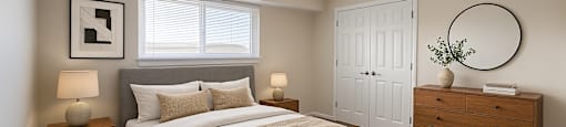 A bedroom with a large bed, two nightstands, and a dresser.