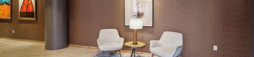 a lobby with two chairs and a table and a painting