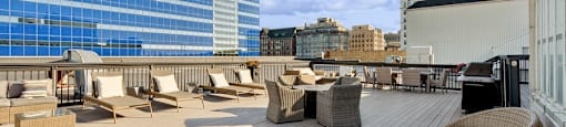a rooftop deck with chairs and tables on a skyscraper