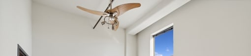 an empty bedroom with a ceiling fan and a window