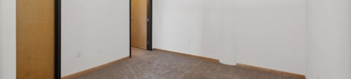 an empty living room with white walls and a door to a hallway