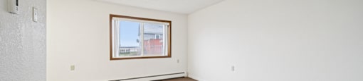 A room with a window and carpeted floor.