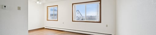 A room with a carpeted floor and two windows.