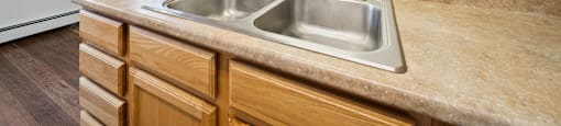 A kitchen with a sink and wooden cabinets.