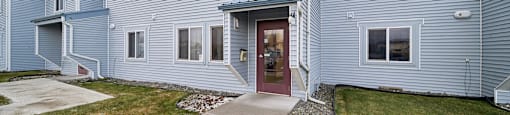 A house with a grey exterior and a red door.