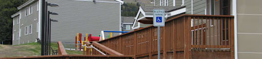 apartment home with a deck and a playground in front of it at Conifer Woods Apartments, Homer, 99603