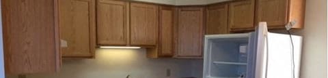 an empty kitchen with an open refrigerator at Woodridge Apartments, Alaska