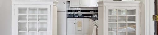 a white kitchen with white cabinets and a yellow rug at The Bryant at Oak Park I & II, Oak Park