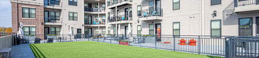 A sunny day at a modern apartment complex with a green lawn and a clear blue sky.