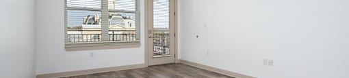 A room with a ceiling fan and a sliding glass door leading to a balcony.