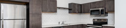 A modern kitchen with a white island and dark brown cabinets.