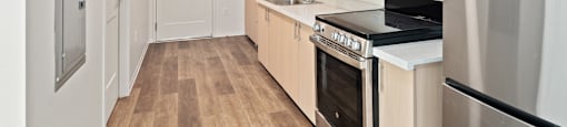 A kitchen with a refrigerator, oven, and sink.