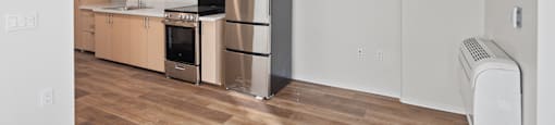 A kitchen with a refrigerator, oven, and cabinets.