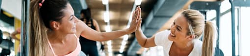 two women giving each other a high five while doing push ups in the gym at Morea Apartments, Pompano Beach, Florida