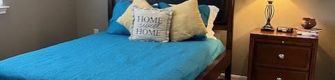 a bedroom with a bed with a blue comforter and pillows