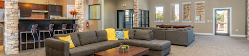 A spacious living room with a stone fireplace and grey couches.