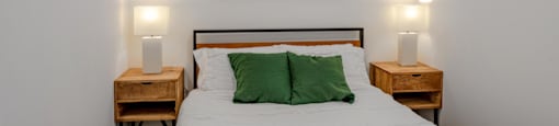 a bedroom with a bed with green pillows and a painting on the wall
