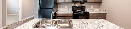 A kitchen with a granite countertop and stainless steel appliances.