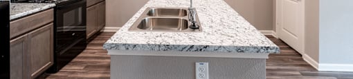 A kitchen with a granite countertop and stainless steel appliances.