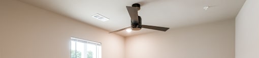 A room with a ceiling fan and a window.