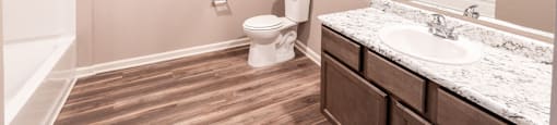 A bathroom with a toilet, sink, and mirror.