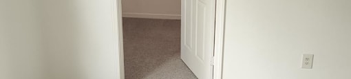 A white room with a white door and a white carpet at Canterbury House apartments in Monticello, Indiana