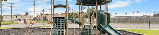 A playground with a green slide and a wooden tower.