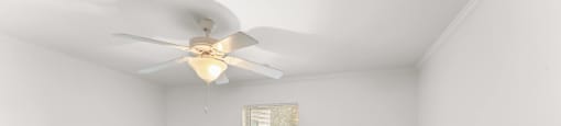 A room with a ceiling fan and carpeted floor.