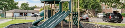 A playground with a green slide and a wooden structure.