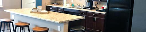 A kitchen with a black refrigerator and wooden floors.
