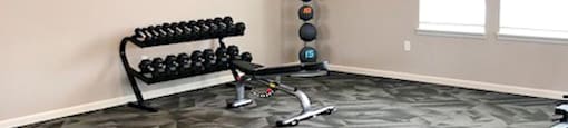 A fitness center with a bench, weights, and a fan.