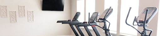 A fitness center with treadmills and a television on the wall.
