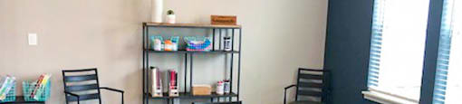 A room with a table, chairs, and a bookshelf.