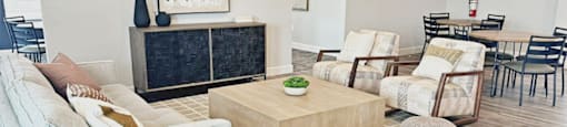 A living room with a grey sofa, a wooden coffee table, and a dining table with chairs.