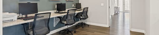 A room with a long desk and chairs and three pictures on the wall.