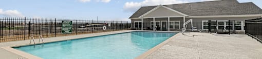 A large outdoor swimming pool with a black fence surrounding it.