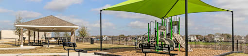 A playground with a green canopy and a slide.