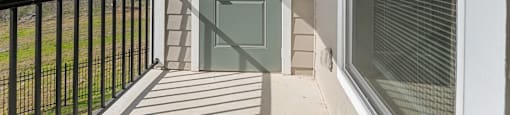 A balcony with a green door and a black railing.