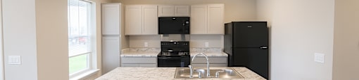 A kitchen with a granite countertop and black appliances.
