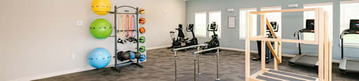 A room with a variety of exercise equipment including a treadmill, stationary bike, and a rowing machine.