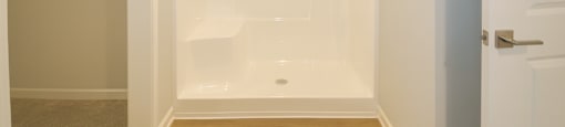 A white bathroom with a walk-in shower and a towel rack.