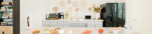 A kitchen with a marble countertop and a black refrigerator.