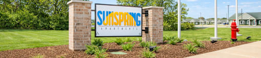 A sign for Sunspring apartments with flags