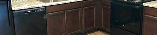 A kitchen with dark wood cabinets and black appliances.