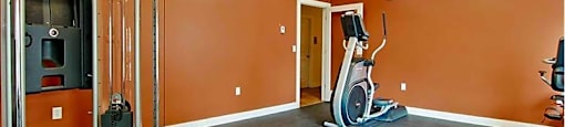 A gym with orange walls and a variety of equipment.