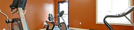 A gym with orange walls and a variety of exercise equipment.