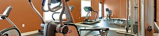 A gym with a treadmill, elliptical trainer and a weight machine.