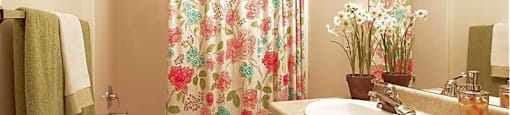 A bathroom with a floral shower curtain and a white sink.